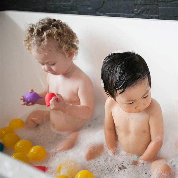 niños jugando en la bañera con animales de silicona
